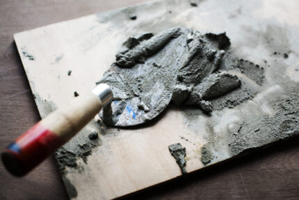 Brick trowel with cement on wood surface