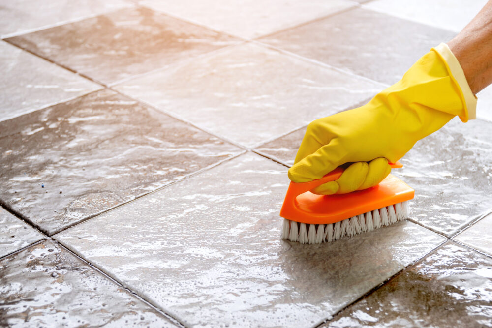 Person cleaning a tiled floor with a scrub brush