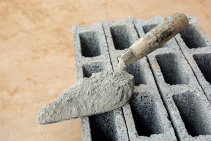Close up of a brick trowel with cement powder on concrete bricks