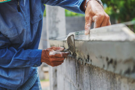 Close-up of a worker plastering a wall with a brick trowel